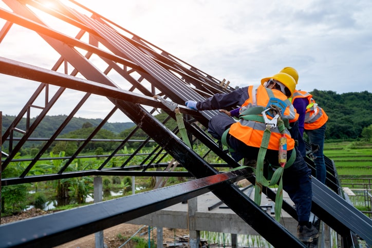 Dachdecker auf Dachgerüst abgesichert mit Kletterausrüstung