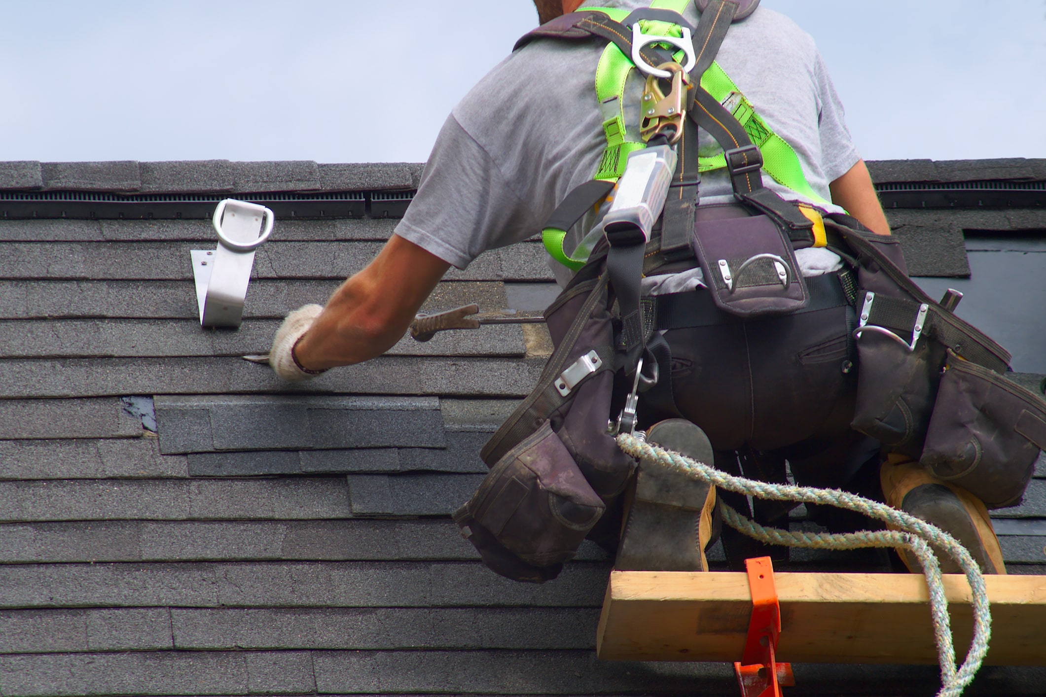 Dachdecker arbeitet auf Dach, gesichert mit Kletterausrüstung